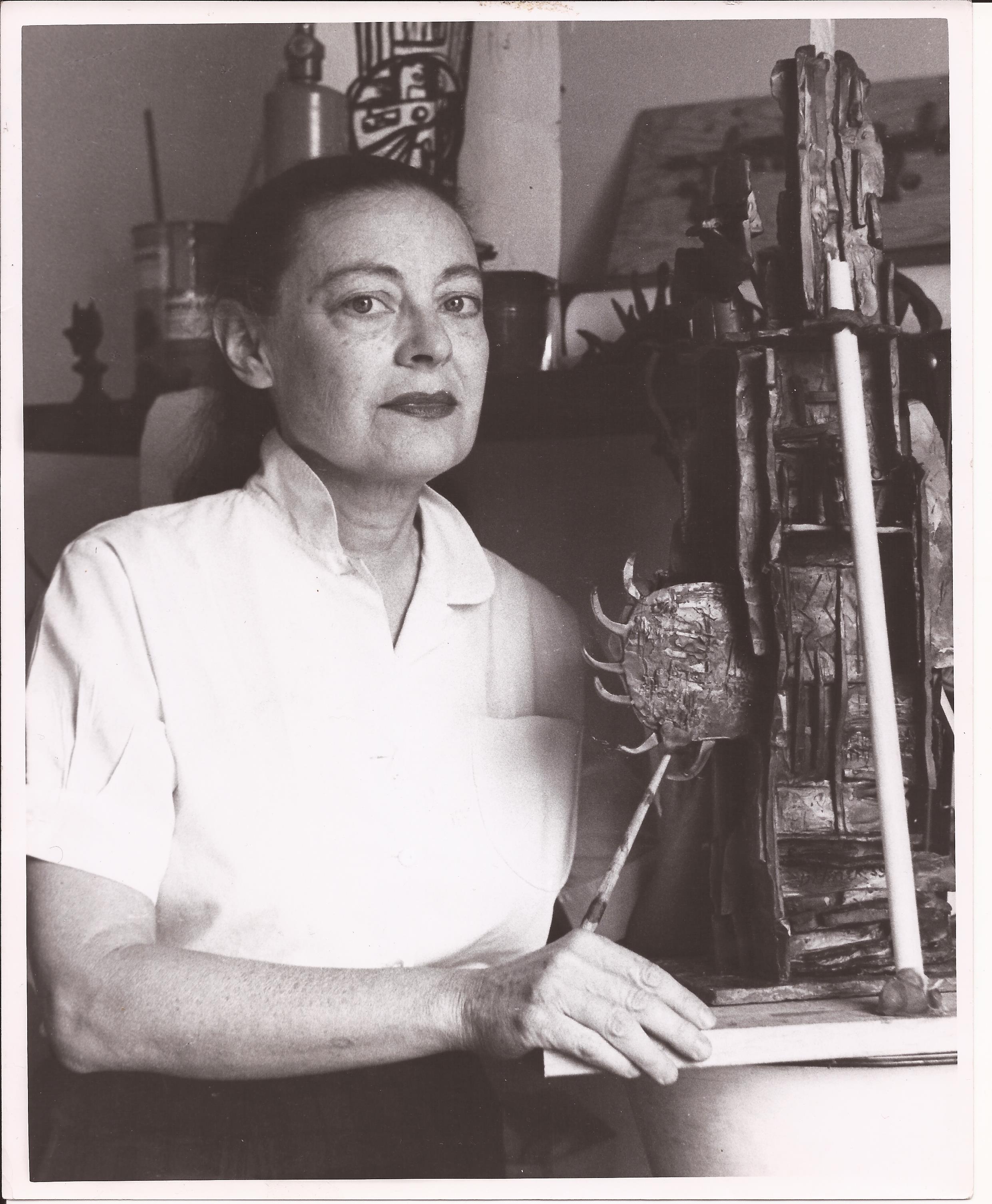 Dorothy Dehner seated in her studio beside a sculpture.